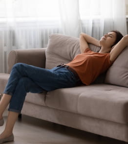 Jovem mulher a relaxar no sofá depois de aprender a relativizar.